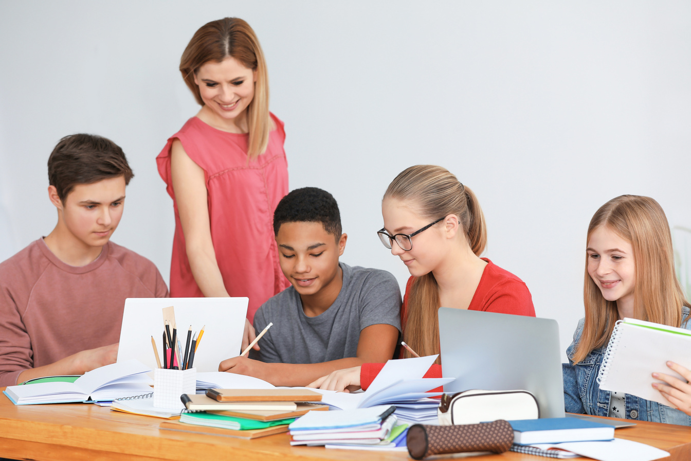 Group of Teenagers Doing Homework with Teacher in Classroom